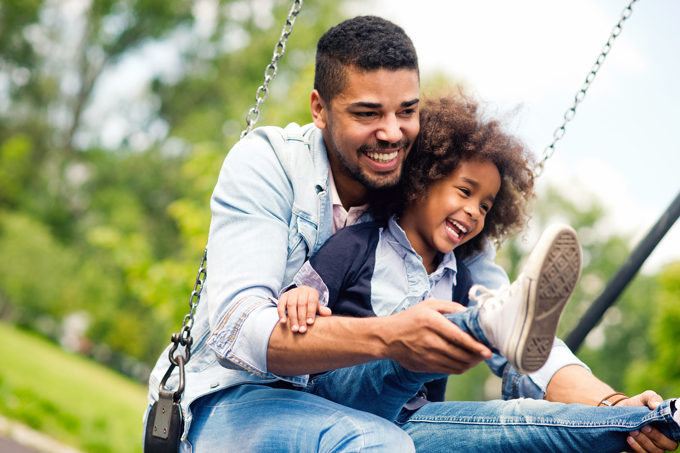 Father and son swing on a playground.