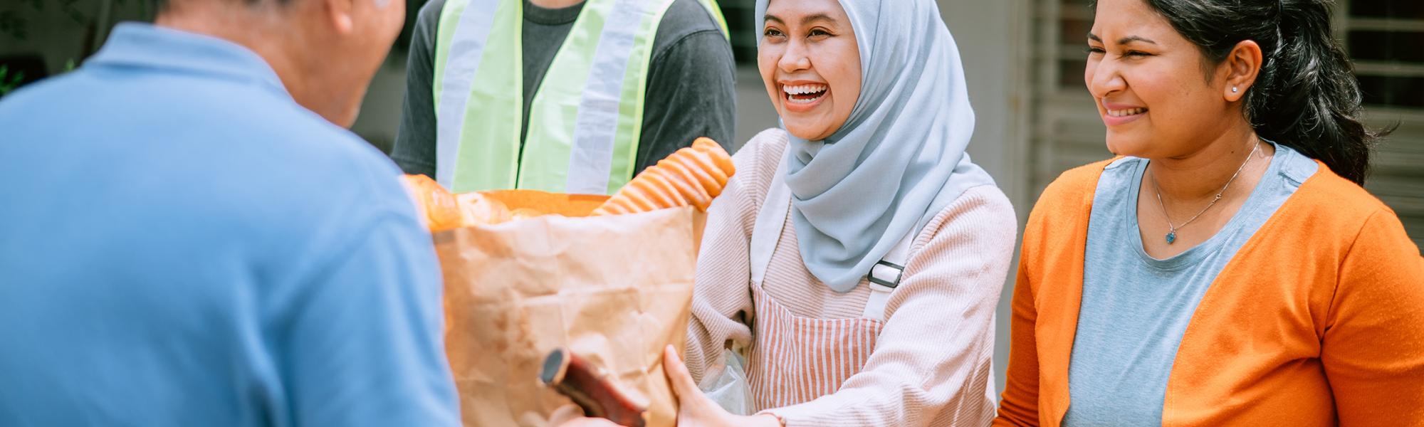 A diverse group of volunteers distributes food at a food pantry.